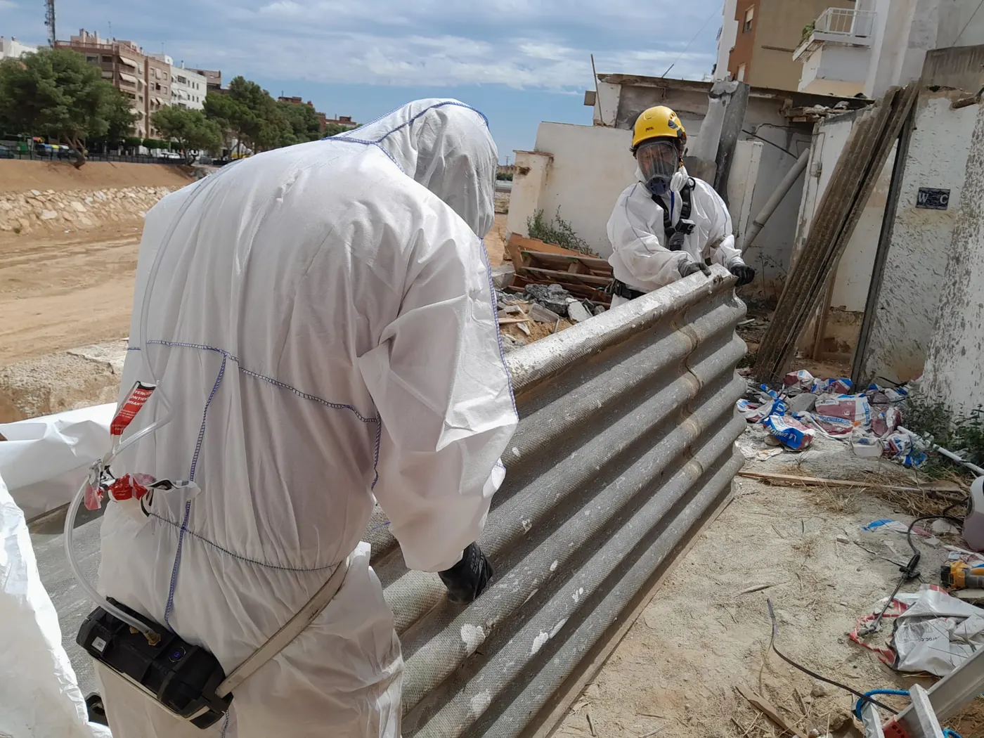 Operario con casco y buzo sujetando una placa ondulada de fibrocemento durante el descenso controlado