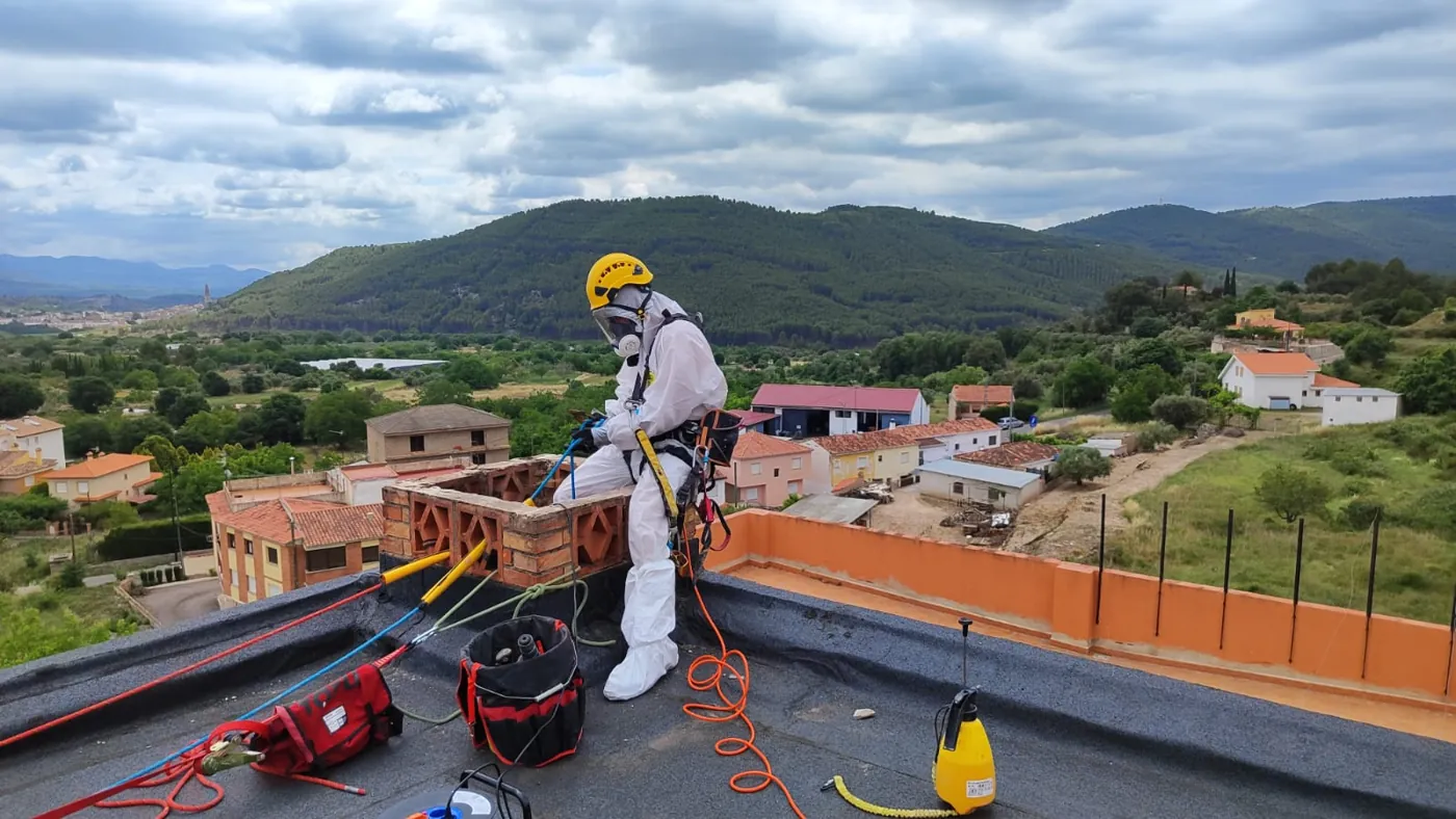 Operario con EPI retirando bajantes de uralita en una azotea de Viver (Castellón)