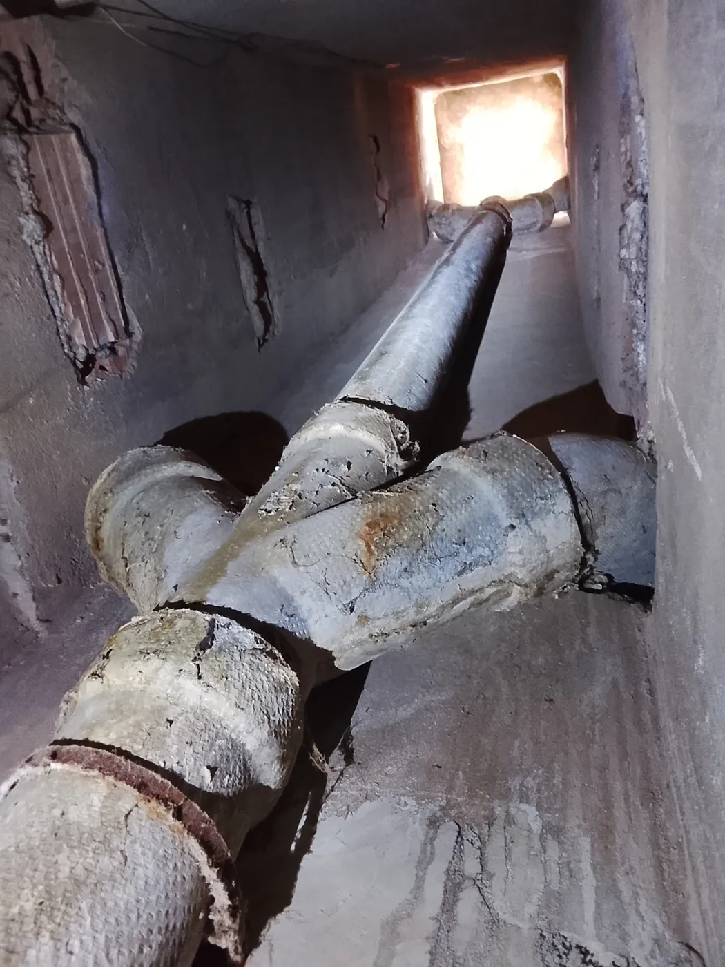 Bajante de fibrocemento con amianto y uniones agrietadas dentro del conducto de un edificio en Viver