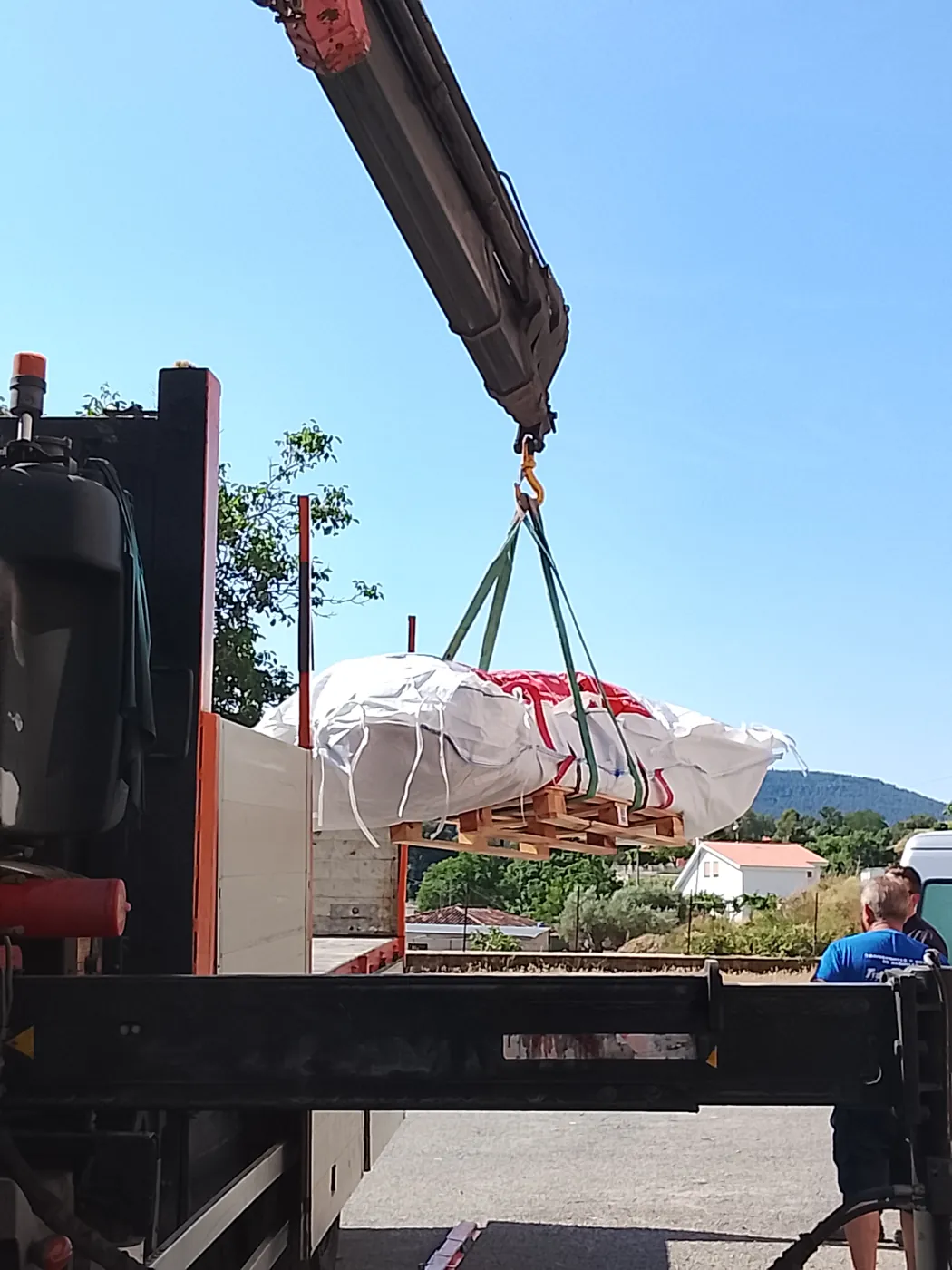 Saca larga con piezas de bajante de fibrocemento sobre palé en el camión