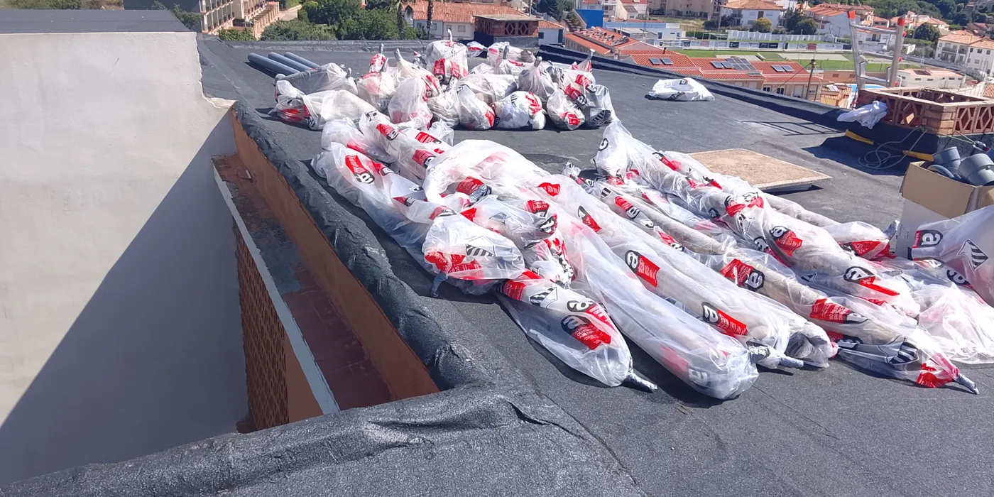 Piezas largas de bajante de fibrocemento envasadas en bolsas con señal de amianto sobre la azotea